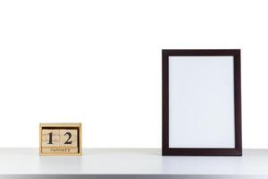 Wooden calendar 12 January with frame for photo on white table and background