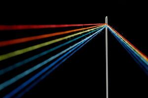 multi-colored threads for sewing in the form of a rainbow pass through an antique needle on a black background photo