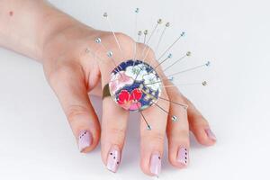 a ring with a small pillow for needles on a hand on a white background photo