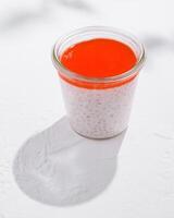 Delicious tapioca pudding with strawberry puree topping on bright background with sharp shadows photo