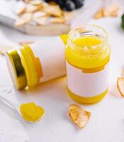 Two jars of ghee with blank labels and a spoonful on white background photo