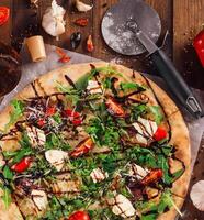 Freshly baked pizza lying on table with ingredients spread around photo