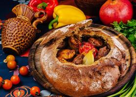 Traditional georgian chanakhi with meat and vegetables in a bread pot standing on a table photo