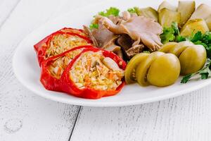 Plate of assorted pickled vegetables with mushrooms and stuffed bell peppers on white table photo