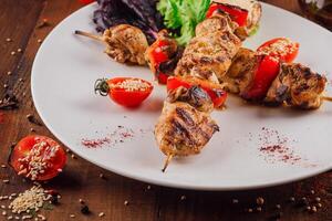 Grilled chicken and bell pepper skewers with cherry tomatoes and spices on a white plate photo
