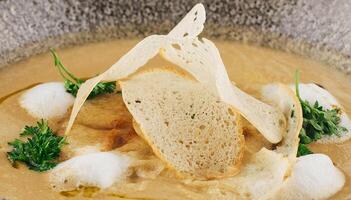 Creamy soup being garnished with bread and parsley in a restaurant setting photo