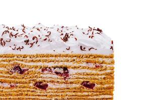 Delicious layered honey cake with cherries and chocolate sprinkles on white background photo