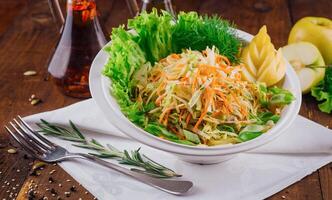 Fresh cabbage salad with apple slices and herbs on wooden table photo