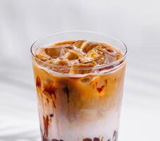 Iced coffee latte with milk and chocolate syrup drizzled on glass photo