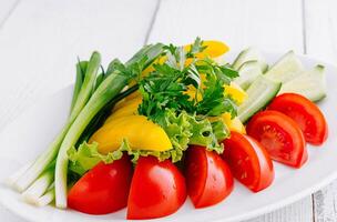 Plate of freshly cut vegetables sitting on white table photo