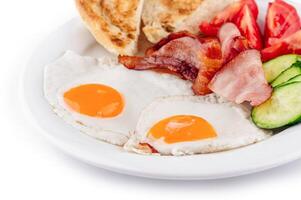 Delicious breakfast plate offering fried eggs and bacon with vegetables and toast photo