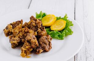 Delicious beef stew with potatoes and onions lying on white plate on white background photo