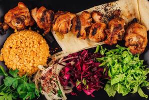 Grilled chicken skewers served with bulgur, salad, and pita bread photo
