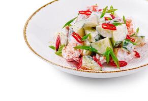 Fresh salad with cucumber and tomato seasoned with red chili pepper on white plate photo