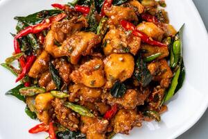 Ayam Tangkap, spices fried chicken original from Aceh, Indonesia. served with leaves such as temurui or curry leaves, pandan leaves and green chili, that are roughly chopped and fried crispy. photo