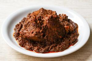 Beef Rendang is a Minang dish originating from the Minangkabau region in West Sumatra, Indonesia. Rendang has been slow cooked and braised in a coconut milk seasoned with a herb and spice mixture photo