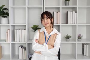 Confident Young Female Office Worker Posing in Modern Workspace with Shelves and Plants in Background photo