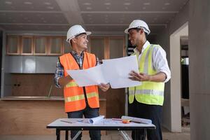 Engineers Discussing and Planning Construction Project While Holding Blueprints in Modern Building Site photo