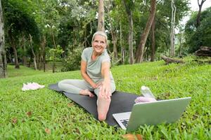 Elderly Woman Sitting and Resting After Yoga Session in a Park, Enjoying Nature and Relaxation photo