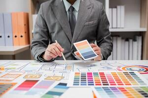 System Developer Analyzing UX UI Plans with Color Swatches and Design Layouts in a Modern Office Setting photo