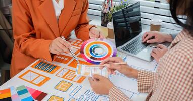 Program Developer Team Collaborates on UXUI Design in Modern Office Setting with Laptops and Color Swatches photo