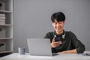 Young Boy Studying Online with Laptop and Smartphone in Modern Home Setting, Smiling and Engaged in Learning photo