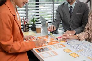 Creative Team Collaborates on UX UI Design Project in Modern Office Setting with Laptops and Design Prototypes photo