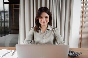 Confident Business Woman Working on Laptop in Modern Office Setting with Natural Light and Professional Ambiance photo