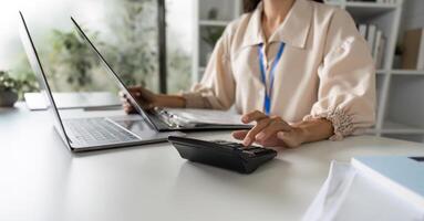 Close-up of Accountant Performing Financial Calculations with Laptop and Calculator in Modern Office Setting photo