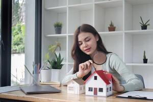 Real Estate Agent Analyzing Model Houses with Magnifying Glass in Modern Office Setting photo