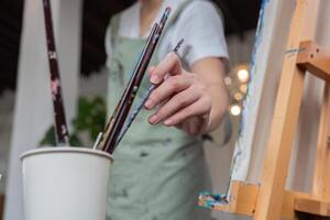 Female Artist Painting on Canvas in Studio with Brushes and Easel, Capturing Creative Process and Artistic Expression photo
