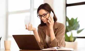 Business Conversation. Smiling manager wearing specs making phone call, talking with partners, using laptop, copyspace photo