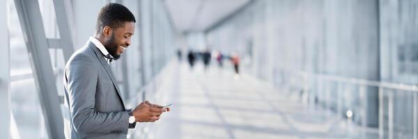 Always in Touch. African American Businessman Texting on Phone, Waiting for Flight at Airport, Side View, Panorama, Copy Space photo
