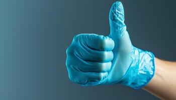 Thumbs Up Gesture with Blue Latex Glove on a Gray Background photo
