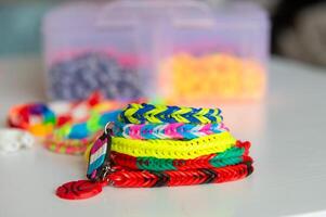 Stack of colorful rubber band bracelets with charm on a white table photo
