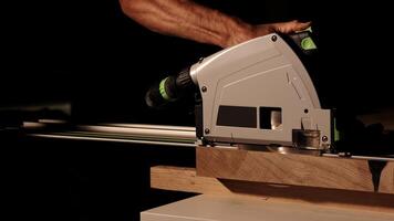 Close-up of a man cuts a wooden plank with an electric circular saw in a workshop. Cutting a piece of wood on a circular saw in backlight. Ideal topics related carpentry, efficient sawing techniques photo