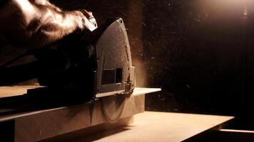 Construction Contractor Cutting To Size Wood Beam Using Portable Circular Saw Close Up. Worker using a circular saw to cut a wood in a factory with selective focus. Industrial Equipment Theme. photo