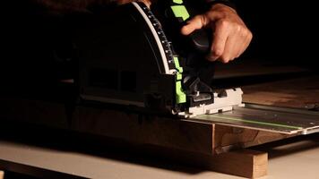 Construction Contractor Cutting To Size Wood Beam Using Portable Circular Saw Close Up. Worker using a circular saw to cut a wood in a factory with selective focus. Industrial Equipment Theme. photo