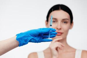 Woman while procedure lip augmentation at cosmetology clinic with beautician. Filler injection for beautiful female lips augmentation with hyaluronic, side view. photo