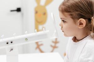 A little girl enjoys an engaging vision game on state-of-the-art ophthalmic equipment. The Rainbow system enhances eyesight in a comfortable and welcoming environment. photo