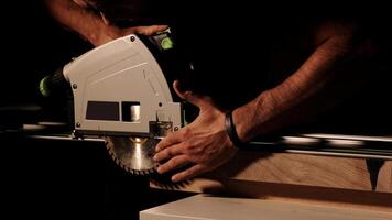 Construction Contractor Cutting To Size Wood Beam Using Portable Circular Saw Close Up. Worker using a circular saw to cut a wood in a factory with selective focus. Industrial Equipment Theme. photo
