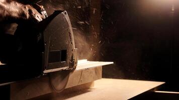Close-up of a man cuts a wooden plank with an electric circular saw in a workshop. Cutting a piece of wood on a circular saw in backlight. Ideal topics related carpentry, efficient sawing techniques photo