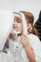 Close-up of a little girl with deep eyes undergoing vision diagnostics using a slit lamp in an ophthalmology clinic. A perfect moment highlighting the importance of caring for children's vision photo