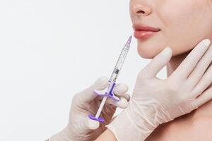 Woman while procedure lip augmentation at cosmetology clinic with beautician. Filler injection for beautiful female lips augmentation with hyaluronic, side view. photo