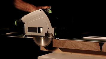 Close-up of a man cuts a wooden plank with an electric circular saw in a workshop. Cutting a piece of wood on a circular saw in backlight. Ideal topics related carpentry, efficient sawing techniques photo