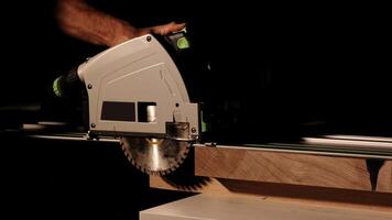 Carpenter using circular saw for cutting wooden plank. Man worker building wooden frame. Carpentry tools in use. Cutting a piece of wood in furniture factory. photo