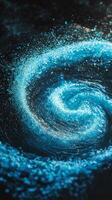 Dynamic turquoise particles whirl together, forming an intense vortex that glows with cosmic energy against a shadowy background, creating a mesmerizing visual spectacle. photo