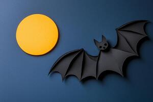 beautifully crafted paper bat soars across a deep blue sky, its wings intricately layered in black and grey, with a striking yellow moon illuminating the night. photo
