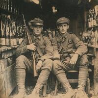 Two soldiers from the First World War sit confidently with their rifles in a vintage setting filled with bottles capturing a moment of camaraderie in wartime. photo