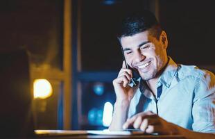 Happy Employee. Office Manager Talking On Cellphone Using Tablet Computer Working Overnight At Workplace. Copy Space photo